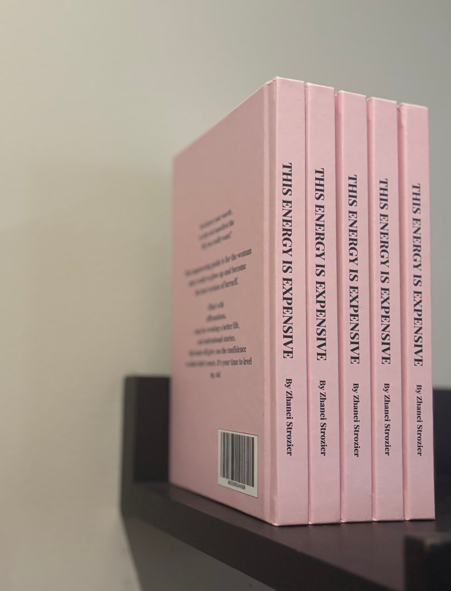 Set of pink books titled 'This Energy is Expensive' on a shelf.