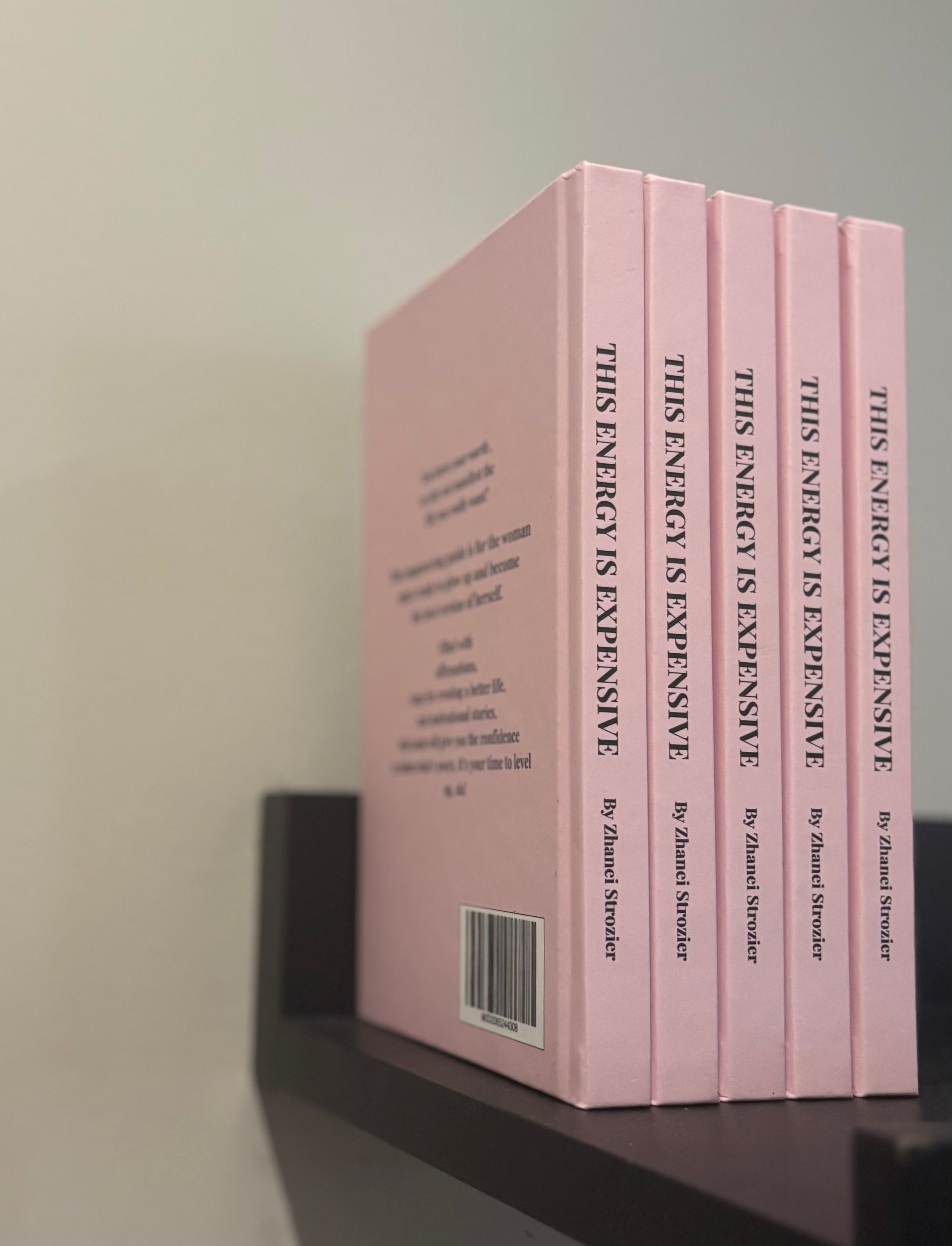 Set of pink books titled 'This Energy is Expensive' on a shelf.